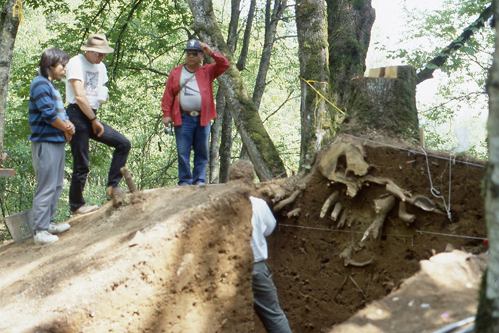 Des personnes sont réunies au sommet d’un gros tertre ancien qui a été creusé.