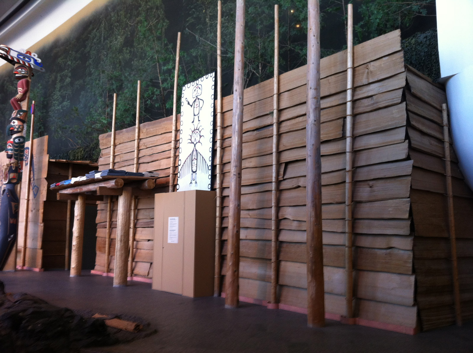 The front of a house showing a series of overlapping horizontal wood planks held upright by small posts