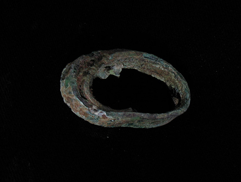 A small oxidized metal hoop, that is greenish in color.