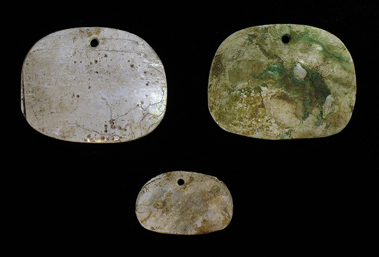 Three pieces of flat abalone shell shaped into ornaments.