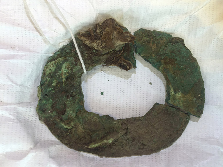 A large broken oxidized metal hoop, greenish in color.