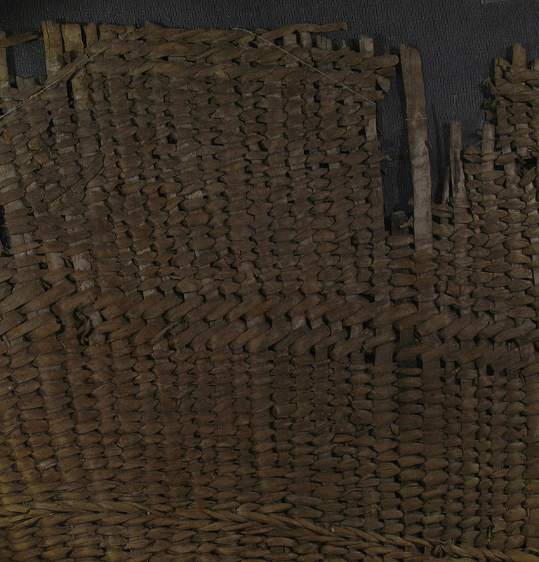  A fragment of woven basketry. The weaving material is brownish red.