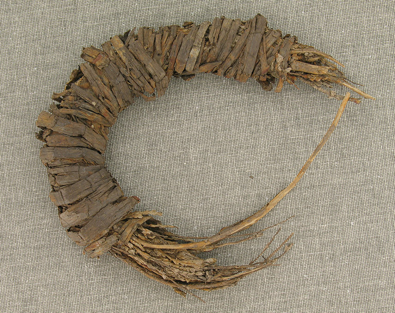 A fragment of a fibrous material in a semi-circle and wrapped with a material that looks like bark.