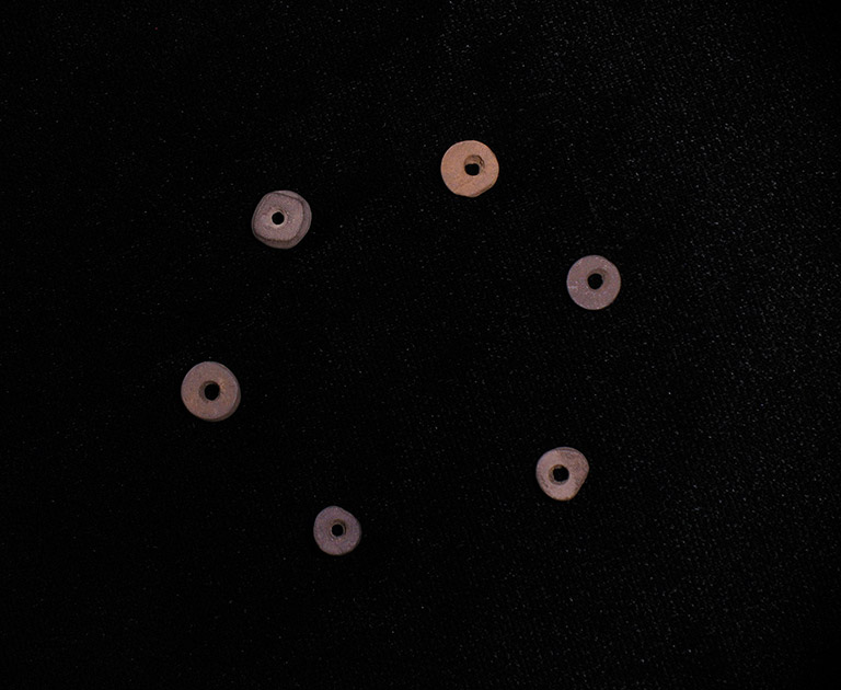 Six small circular stone beads arranged in a circle. 