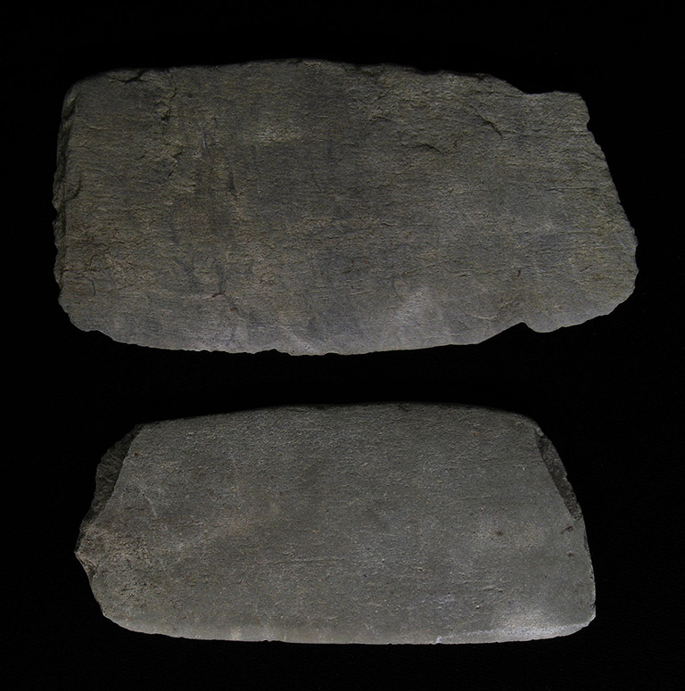 Deux morceaux de pierre grise avec un seul bord aiguisé.