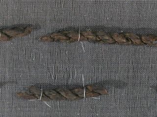 Three pieces of reddish brown fibre are woven into a braid to create a cord.