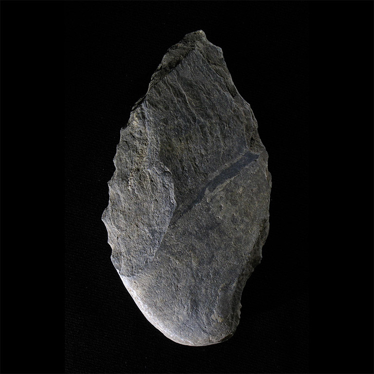 Larger piece of light grey stone, shaped like a leaf, on a black background.