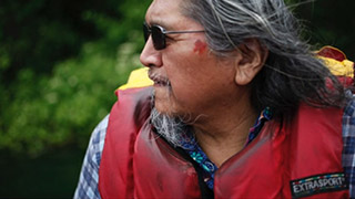 A profile view of an elder, wearing a life jacket.