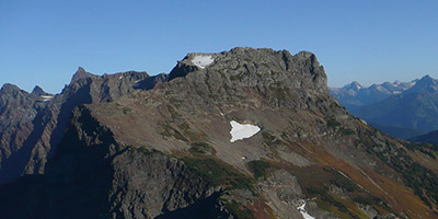 Un pic rocheux de montagne se détache sur un fond de ciel bleu.